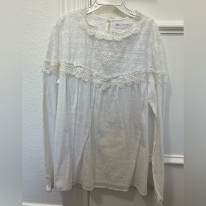 Embroidered long sleeve blouse with lace insert and elastic hem.